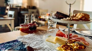 A dining table with a glass cake stand, a glass plate with cheese, and a glass of water. - Relais Valpolicella B&B (Marano di Valpolicella)
