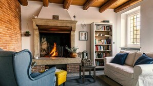 A cozy living room with a fireplace, a bookshelf, and a window. - Relais Valpolicella B&B (Marano di Valpolicella)