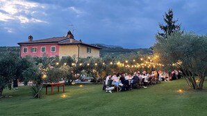 An outdoor dining area with tables and chairs, surrounded by trees and a building in the background. - Relais Valpolicella B&B (Marano di Valpolicella)