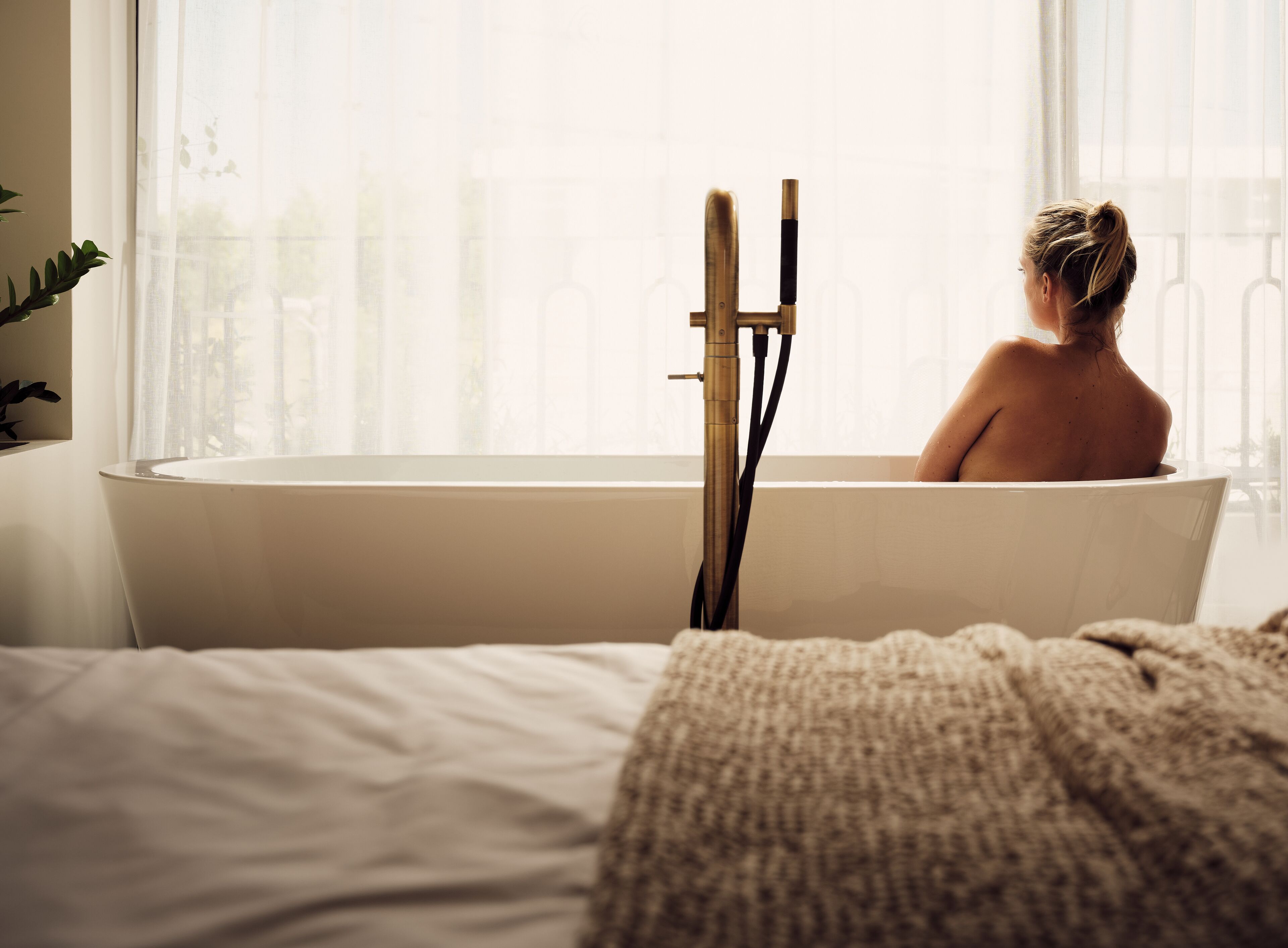 Eine Person sitzt in einer Badewanne, im Hintergrund ein Fenster.