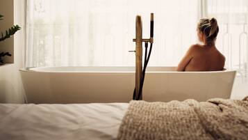 Eine Person sitzt in einer Badewanne, im Hintergrund ein Fenster.