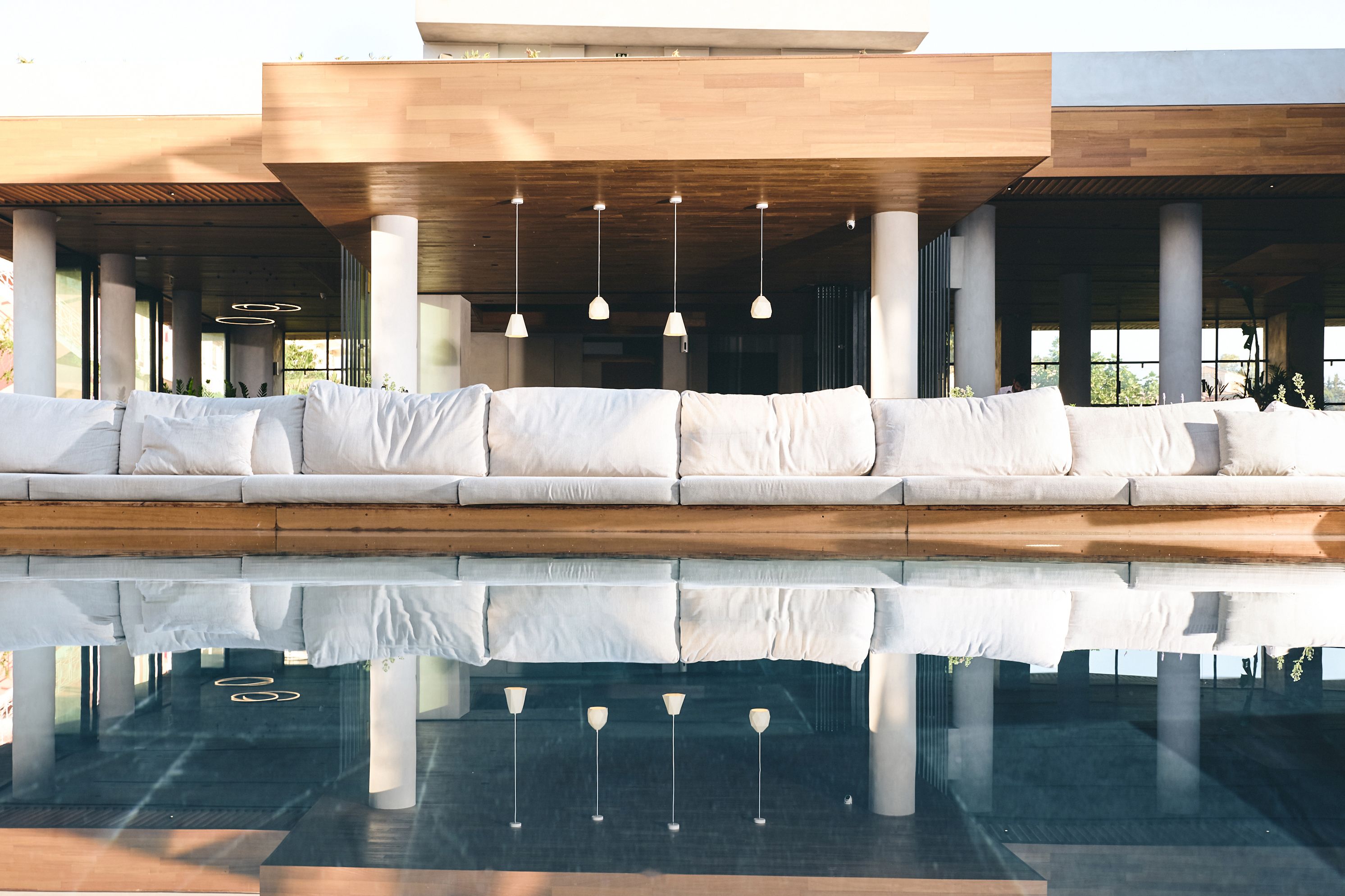 Un'area relax esterna moderna con piscina specchiante e lampade a sospensione.