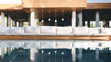 Un'area relax esterna moderna con piscina specchiante e lampade a sospensione.