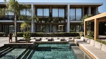 A modern building with a pool, outdoor seating, and a well-maintained garden.