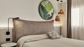 Une chambre d’hôtel bien rangée, avec un lit, une œuvre d’art ronde accrochée au mur, une lampe suspendue et une petite table.