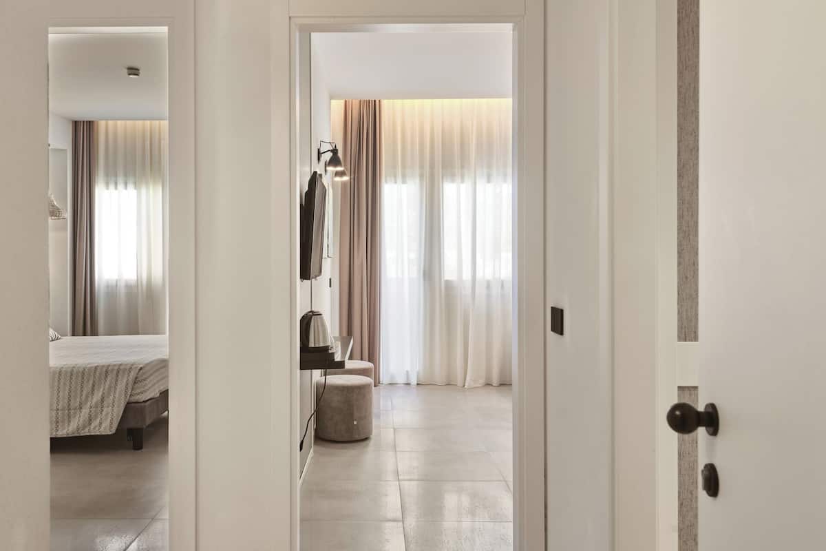 A hotel room with a bed, a bedside table, a lamp, and a window with curtains.