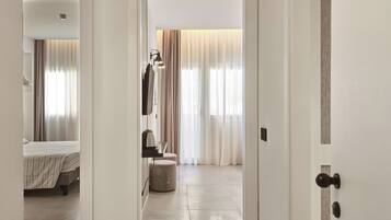 A hotel room with a bed, a bedside table, a lamp, and a window with curtains.