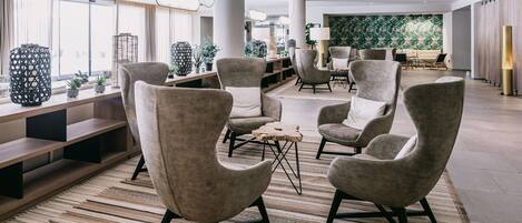 Un espacio lounge moderno con sillones cómodos, una mesa de centro de madera y una alfombra estampada.