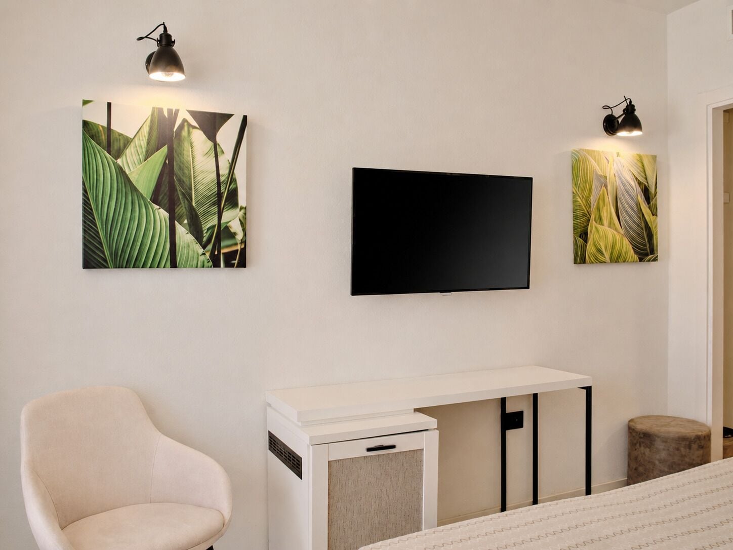 Una habitación con una cama, un escritorio blanco, una silla, un televisor de pantalla plana y dos lámparas de pared.