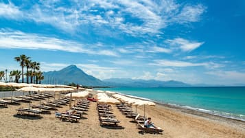 Playa privada, playa de arena negra, camastros y sombrillas 