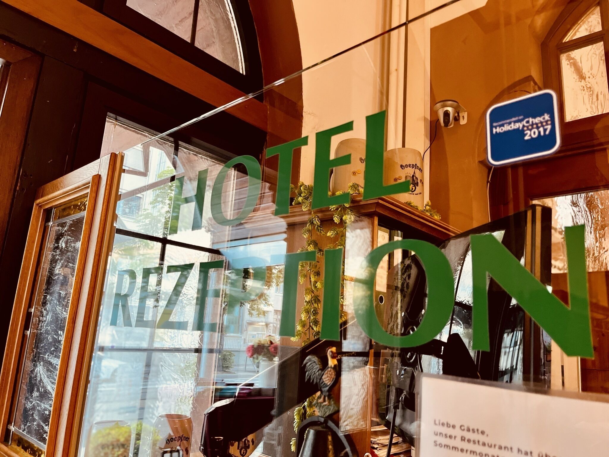 A hotel reception area with a large sign reading "HOTEL RECEPTION" and a sign indicating "Recommended on Holiday Check 2017".