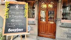 A building with a wooden door and a signboard in front. - Hotel Hoepfner Burghof (Karlsruhe)