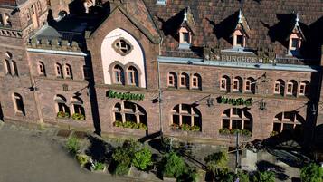 Ein historisches Gebäude mit Rundbogenfenstern und einer Backsteinfassade, mit Schildern für "Burghof" und "Hopfen".