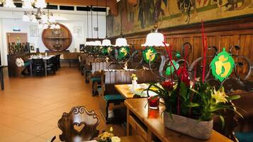A restaurant with wooden furniture, hanging light fixtures, and a mural on the wall.