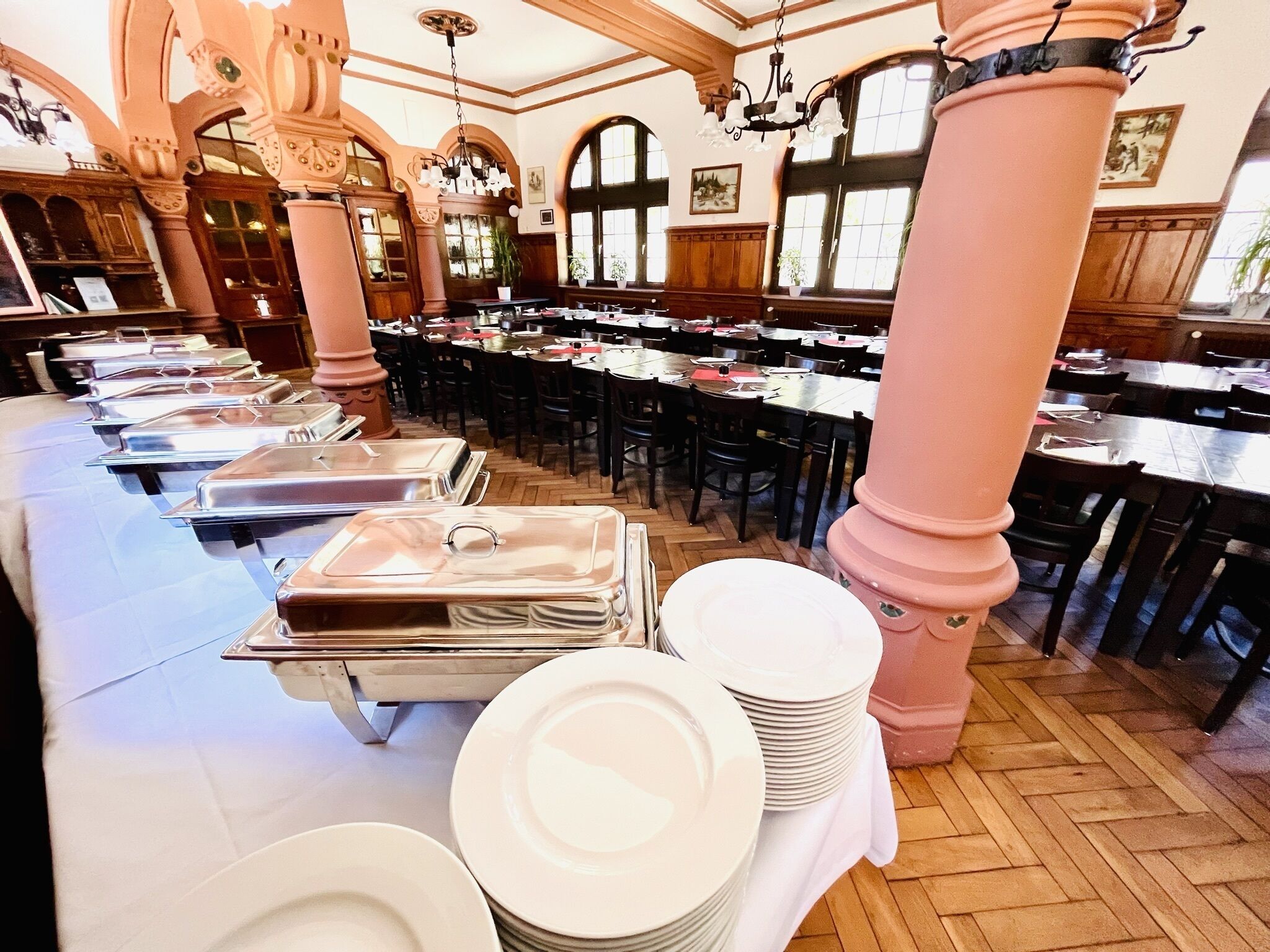 Un comedor espacioso con techos altos, columnas ornamentales y una larga mesa con múltiples estaciones de servicio.