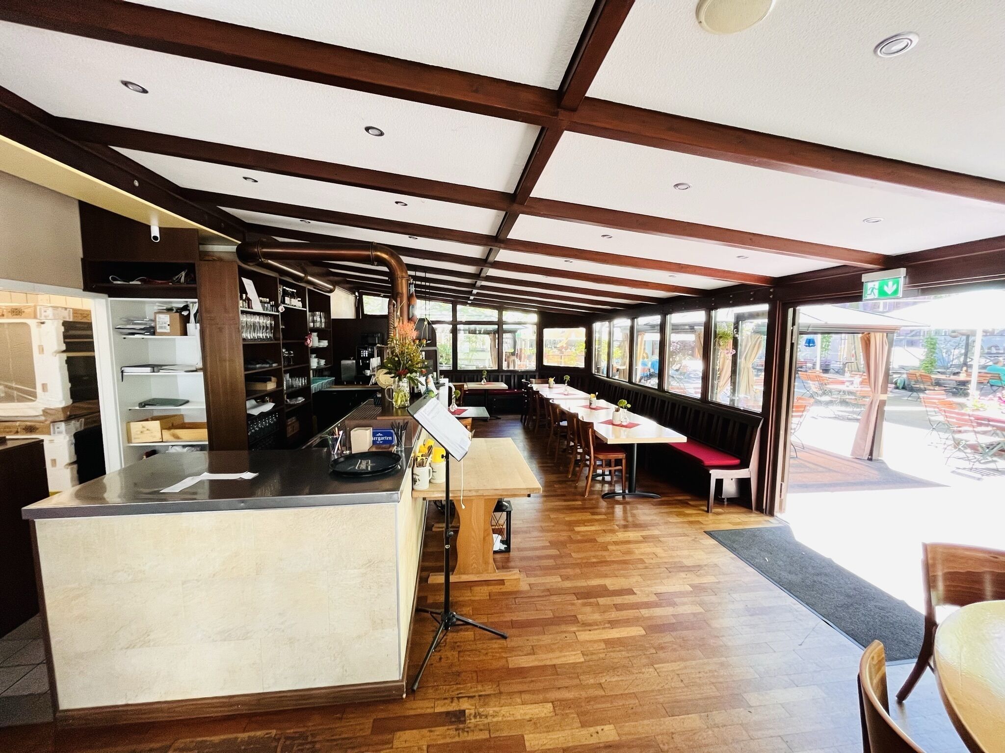 Un restaurant doté d’un long comptoir, d’un plancher en bois et de grandes fenêtres donnant sur l’extérieur.