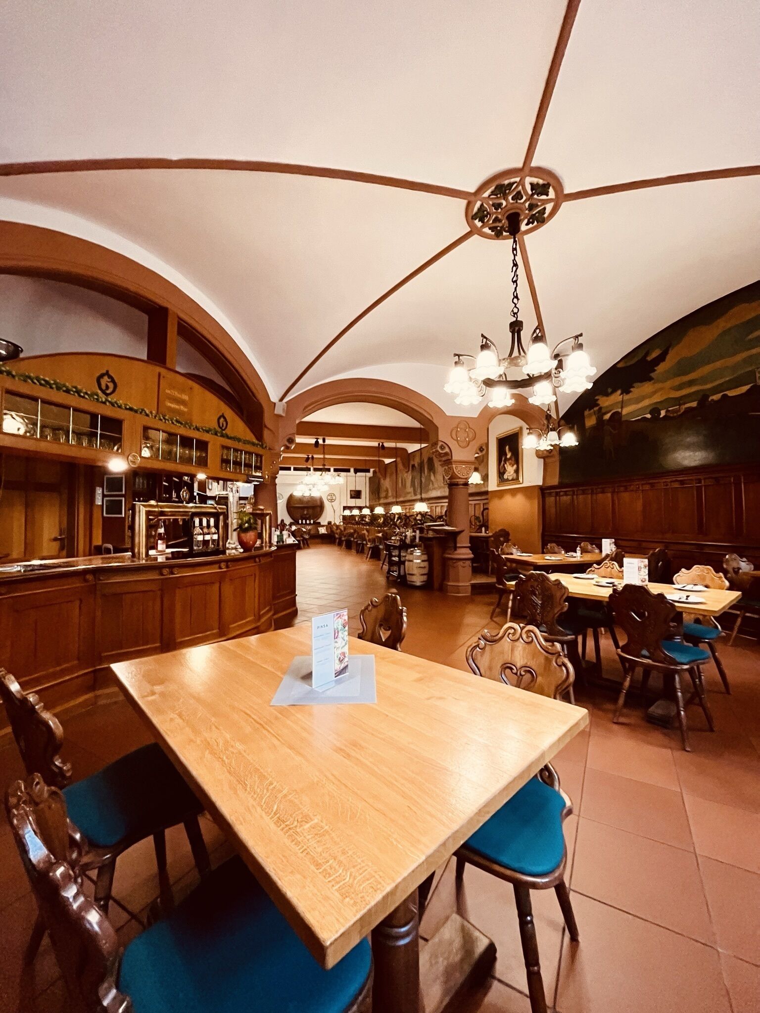 Ein geräumiges Restaurant mit hoher Decke, Holzmöbeln und einer Bar.