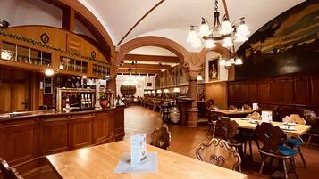 Ein geräumiges Restaurant mit hoher Decke, Holzmöbeln und einer Bar.