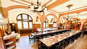 A large dining hall with long tables and chairs, wooden floors, and ornate chandeliers. - Hotel Hoepfner Burghof (Karlsruhe)