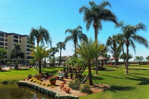 A landscaped garden with palm trees, a small pond, and a gazebo. - Beachfront Resort Style Living - Siesta Beach (Siesta Key)