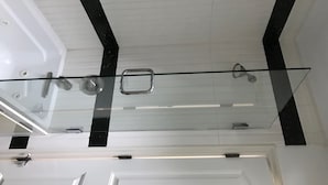 Ein modernes Badezimmer mit Duschkabine aus Glas, weißen Wänden und schwarzen Akzenten.