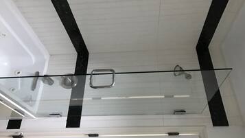 Een bad/douchecombinatie, een bubbelbad, een haardroger, handdoeken