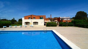 Una piscina con sillones de descanso y un edificio al fondo.