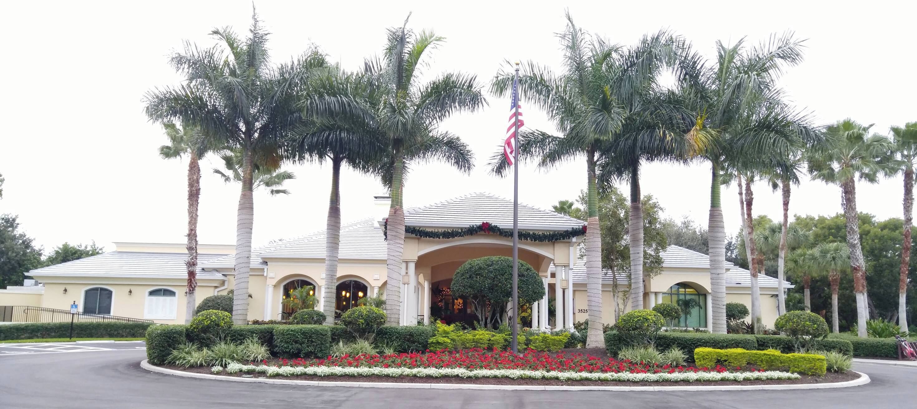 A hotel with a symmetrical facade, palm trees, and a flag.