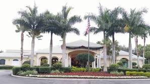 Un hotel con fachada simétrica, palmeras y una bandera.