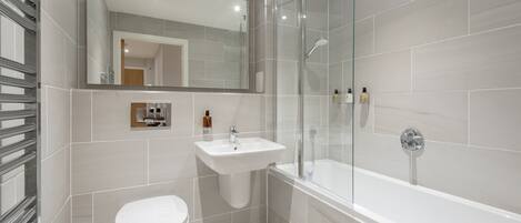 A modern bathroom with a toilet, sink, and glass-enclosed shower.