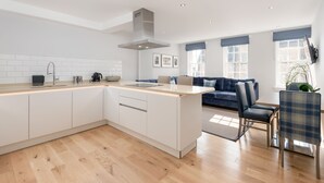 A modern kitchen with a central island, white cabinetry, and a built-in stove. - Destiny Scotland Royal Mile Residence (Edinburgh)
