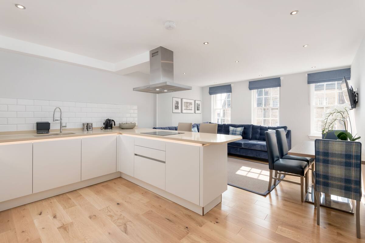 A modern kitchen with a central island, white cabinetry, and a built-in stove.