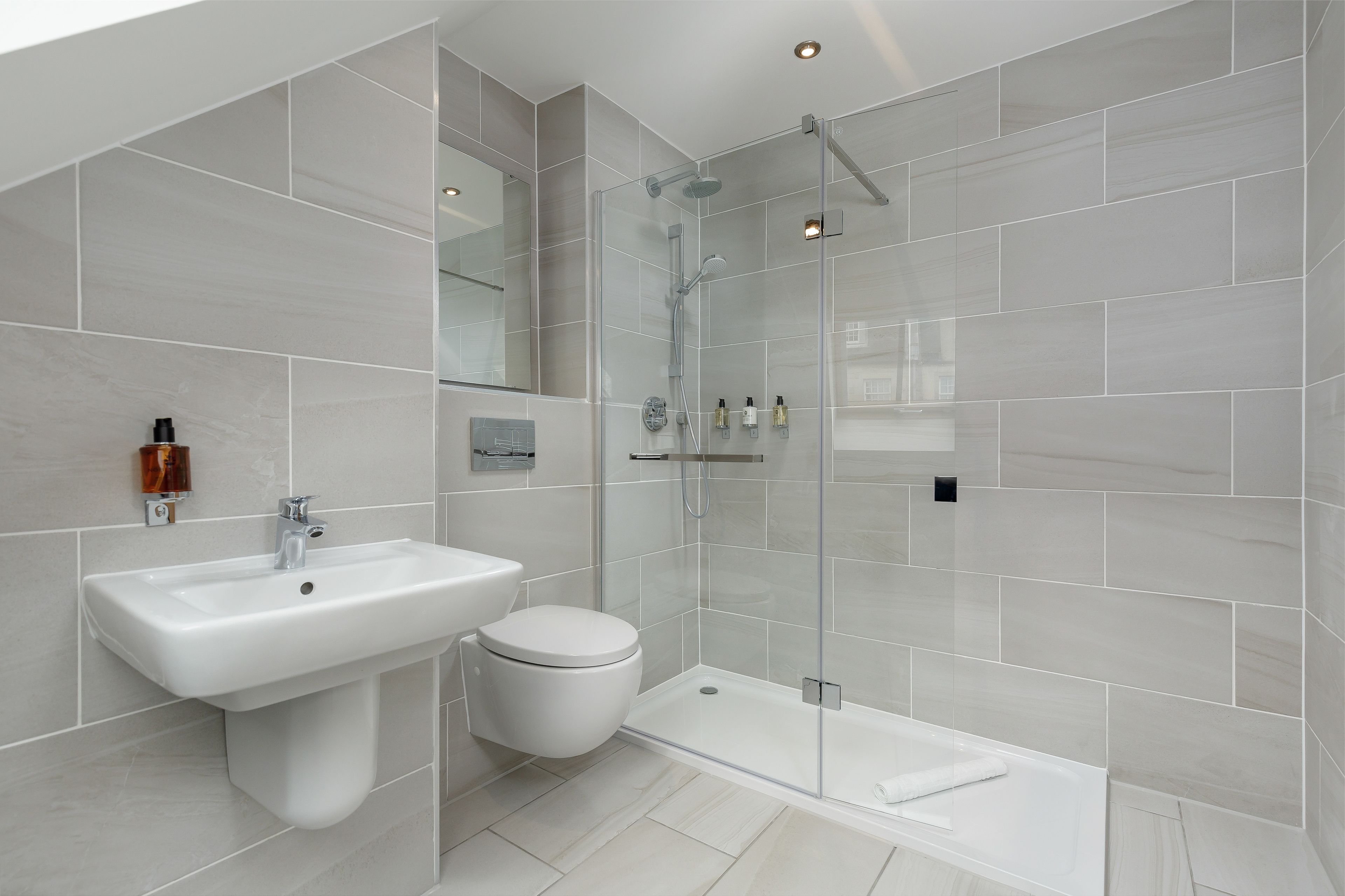 A modern bathroom with a glass-enclosed shower, a white sink, and a toilet.