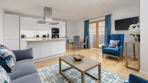 A modern living room with a sofa, a coffee table, and a dining area with a table and chairs. - Destiny Scotland Royal Mile Residence (Edinburgh)