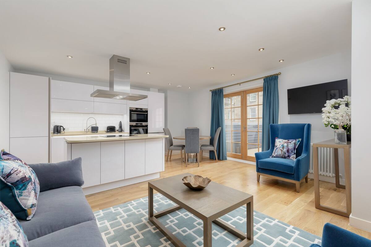A modern living room with a sofa, a coffee table, and a dining area with a table and chairs.