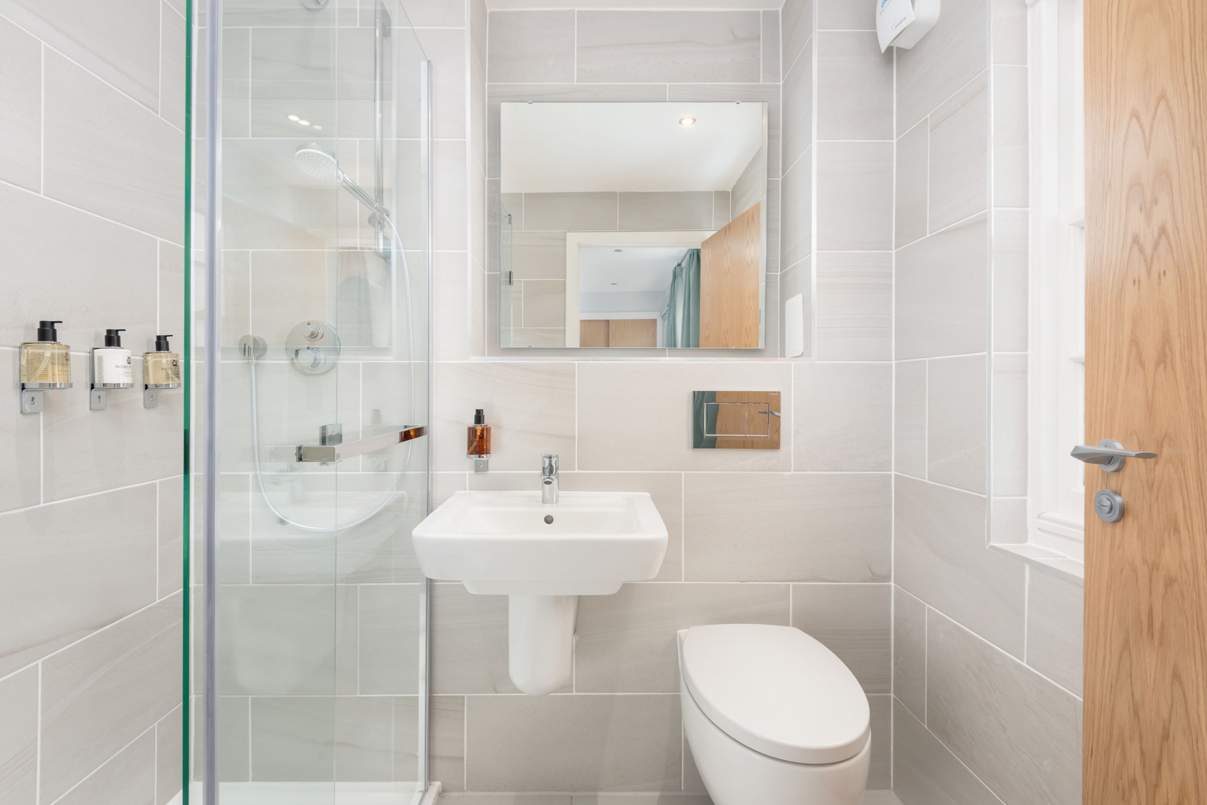 A modern bathroom with a glass shower enclosure, a white sink, and a toilet.