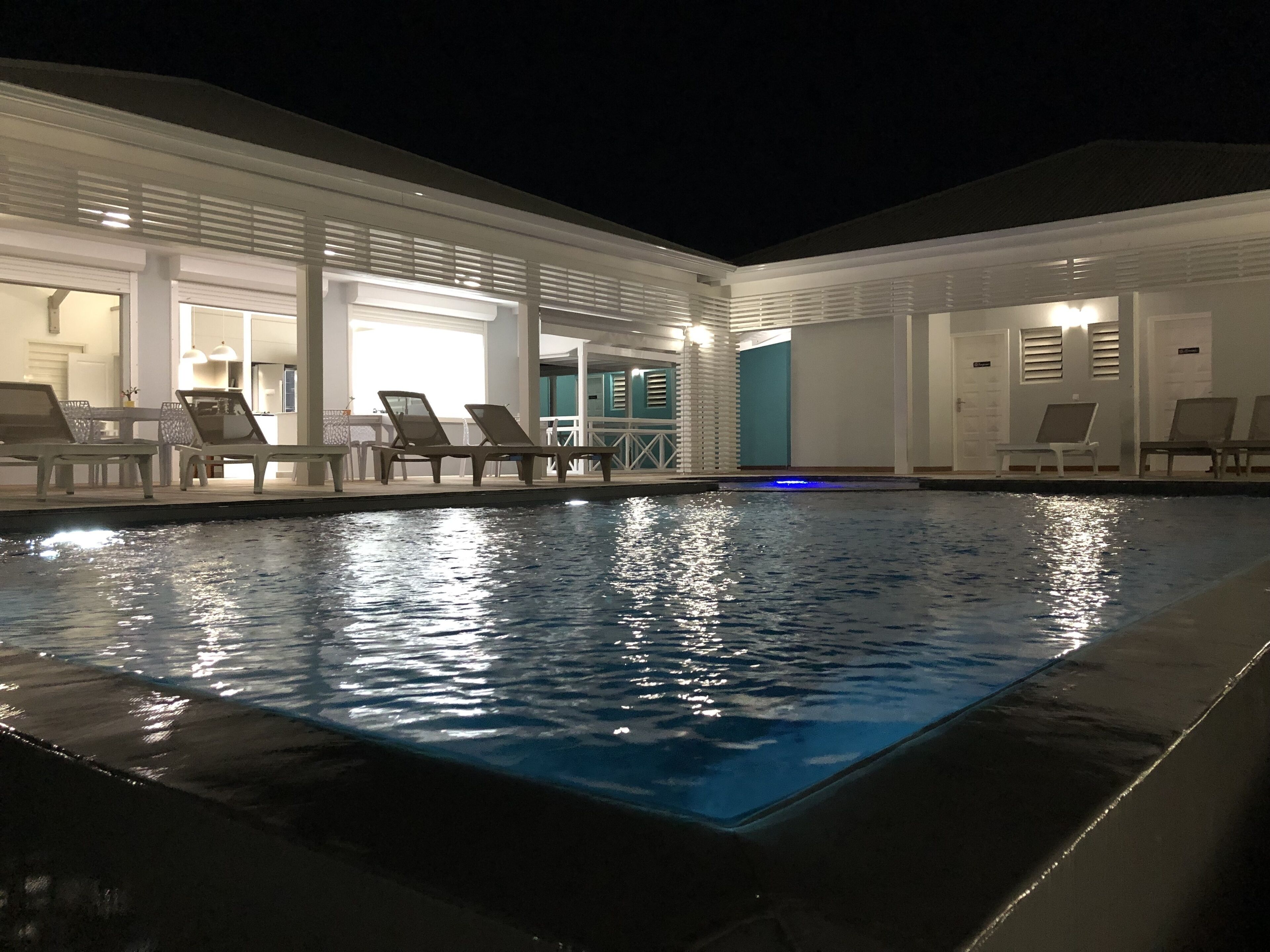 A pool area with lounge chairs and a well-lit interior.