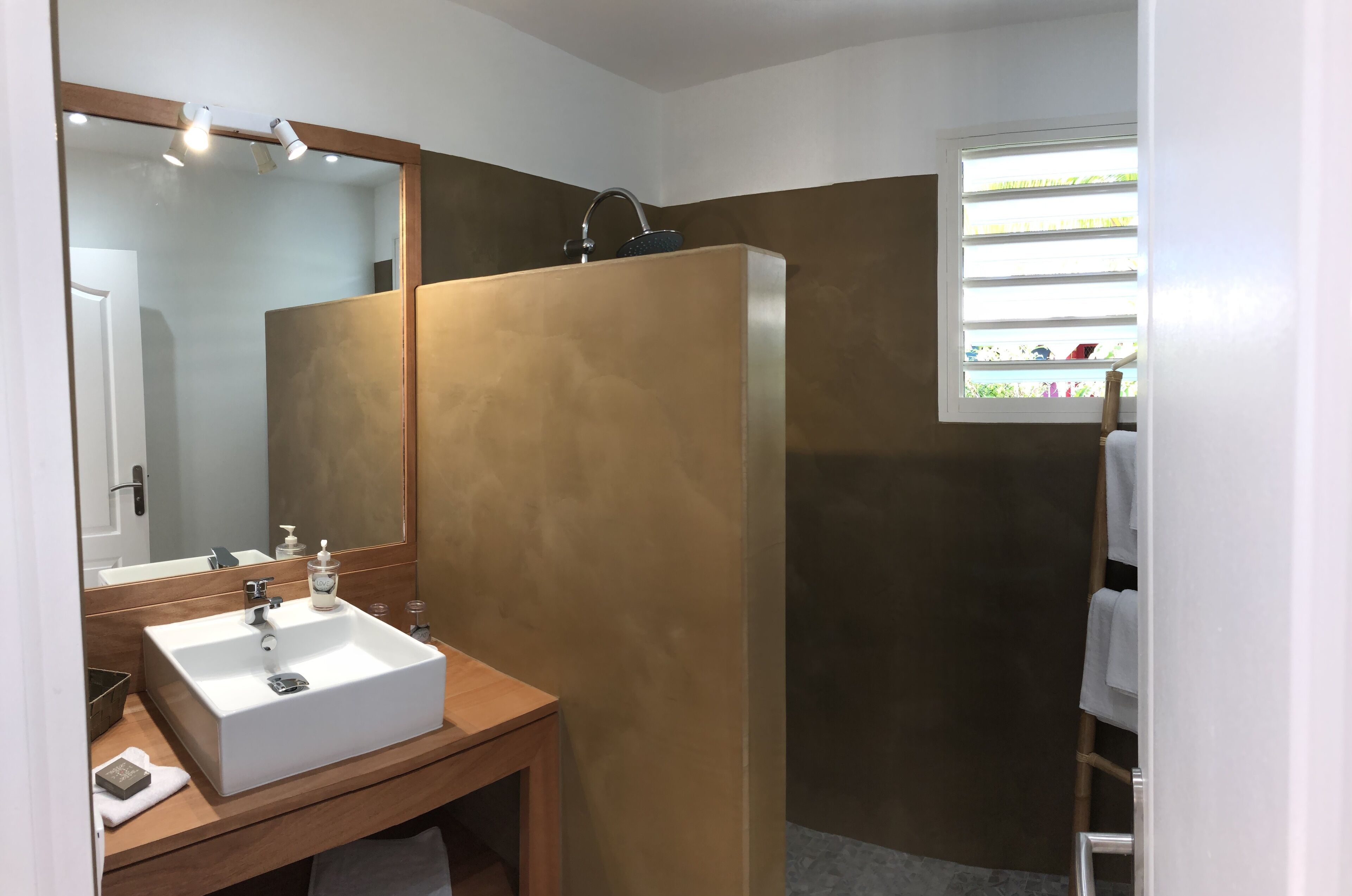 Un baño con lavamanos, espejo y ducha blancos.
