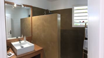 Un baño con lavamanos, espejo y ducha blancos.