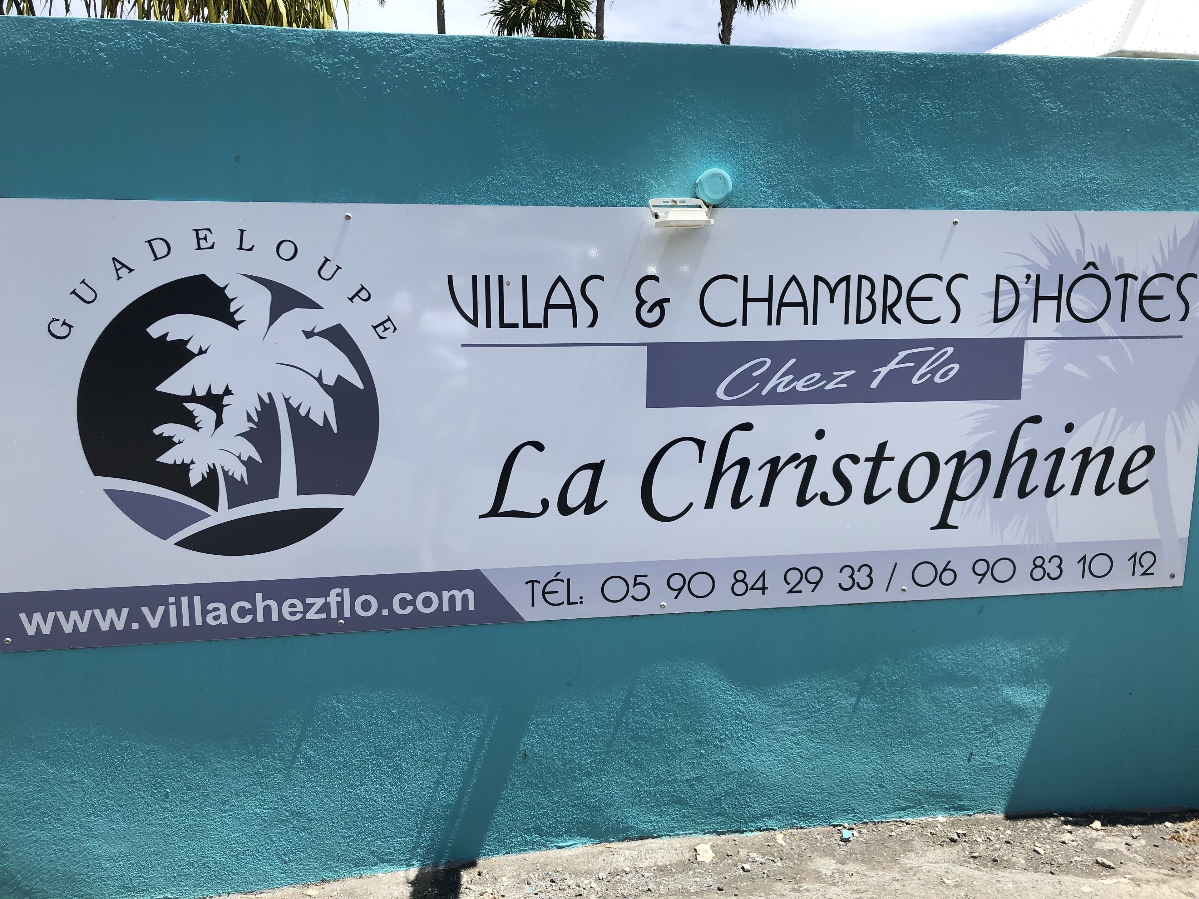 Un cartel que indica 'Villas & Chambres D'Hôtes Chez Flo La Christophine' con información de contacto y una dirección web.