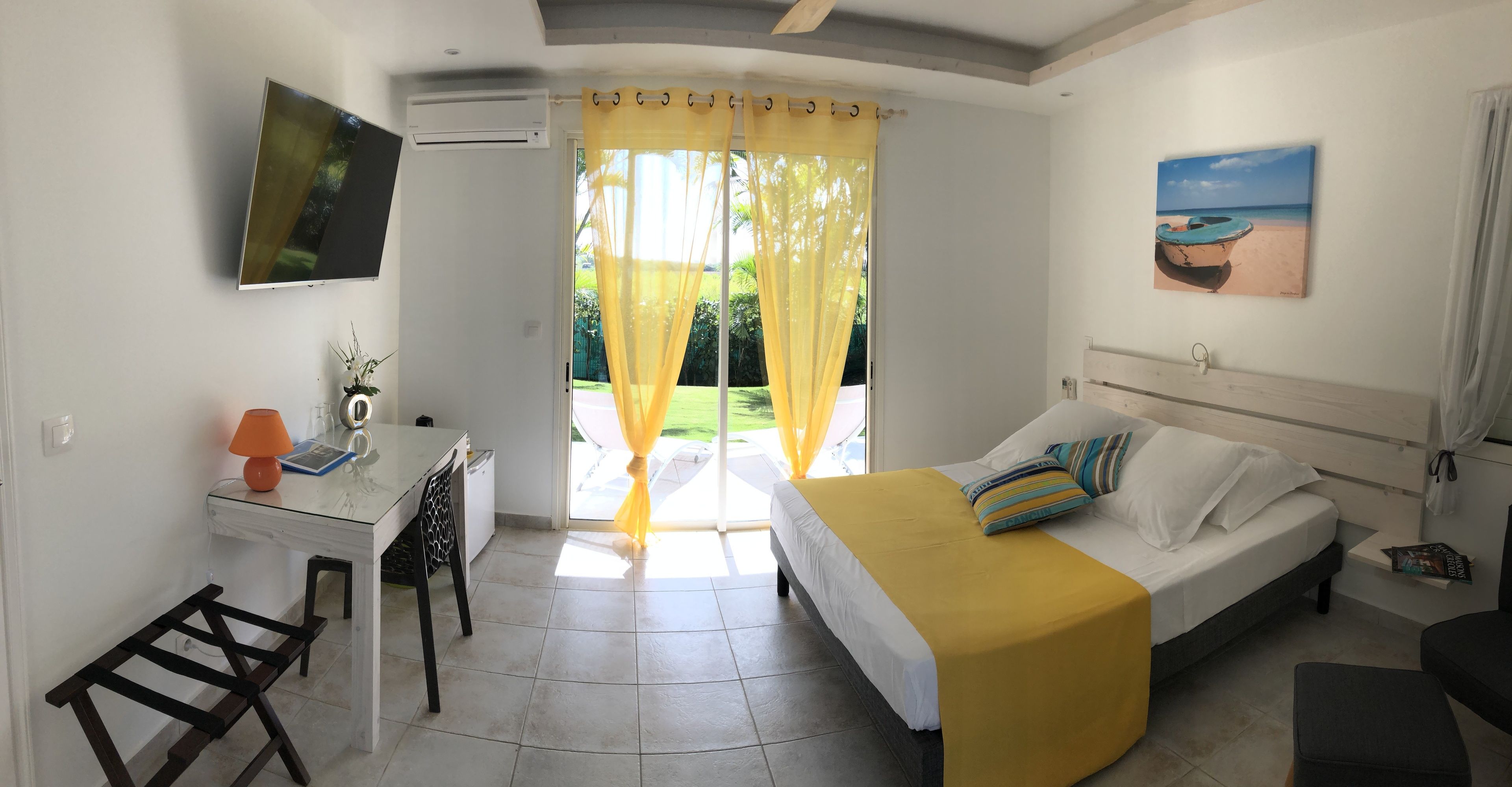 Une chambre à coucher avec un lit, un bureau, une chaise et une fenêtre avec des rideaux.