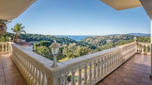 Un balcon avec vue sur une ville côtière et des collines.