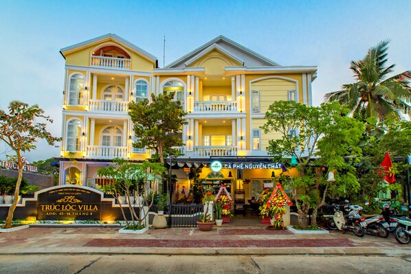A large, multi-story hotel with a prominent entrance, balconies, and a well-maintained garden area. - Truc Loc Villa (Da Nang)