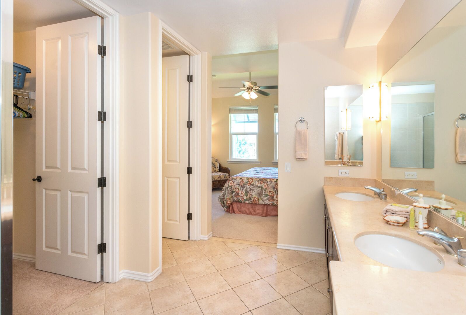 Habitación de hotel con baño que incluye dos lavamanos, un espejo grande y un ventilador de techo.