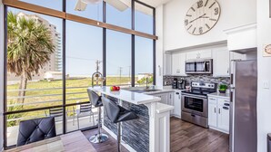 A modern kitchen with a large island, stainless steel appliances, and a view of the outdoors.