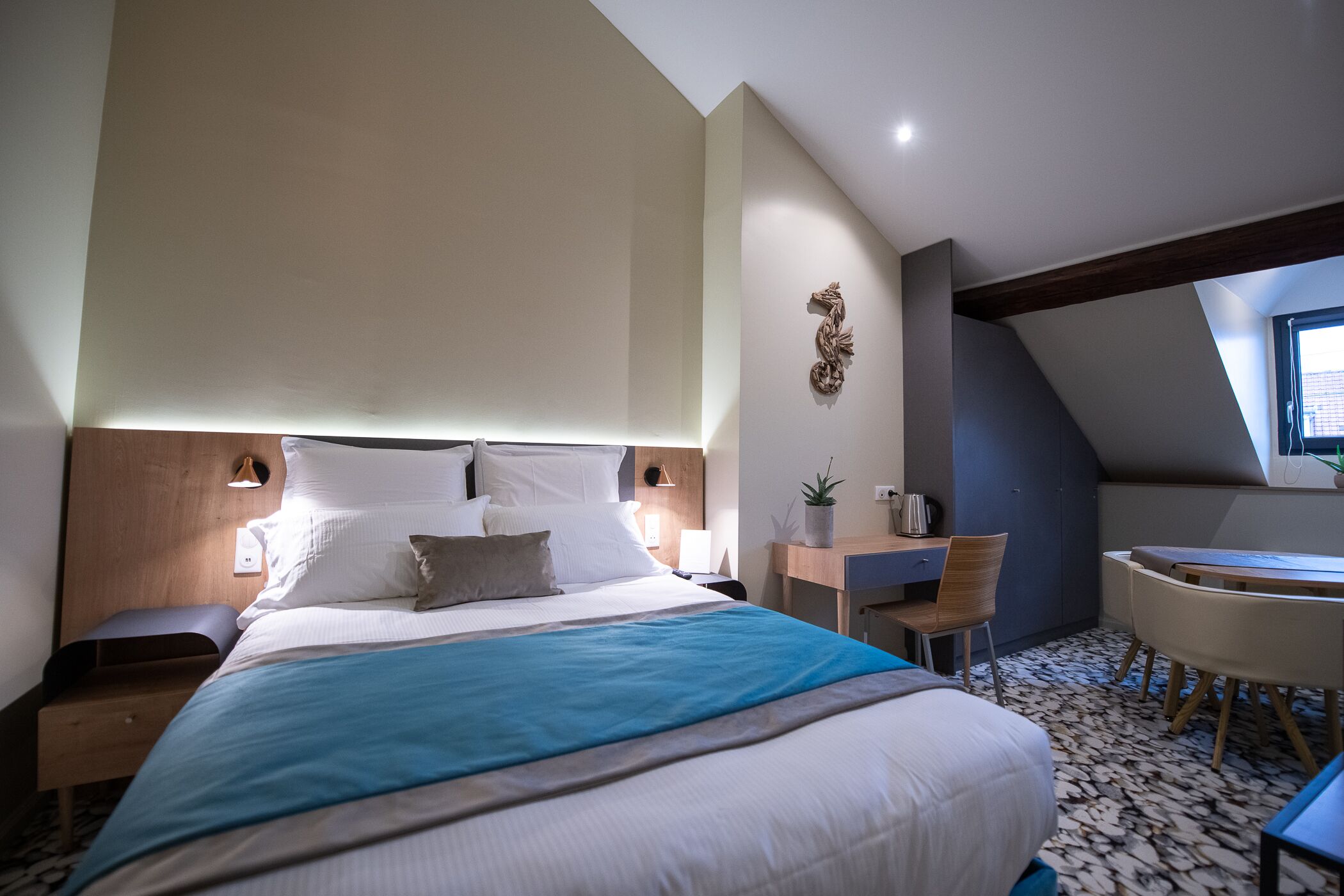 A modern hotel room with a large bed, a desk, and a chair.