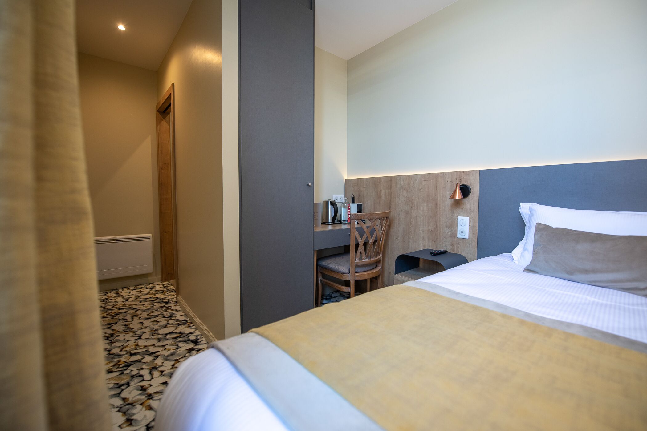 Una habitación de hotel con una cama, un escritorio y una silla.