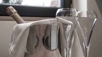 Un recipiente metálico con cubierta de tela, dos vasos de vidrio transparente y una ventana al fondo.