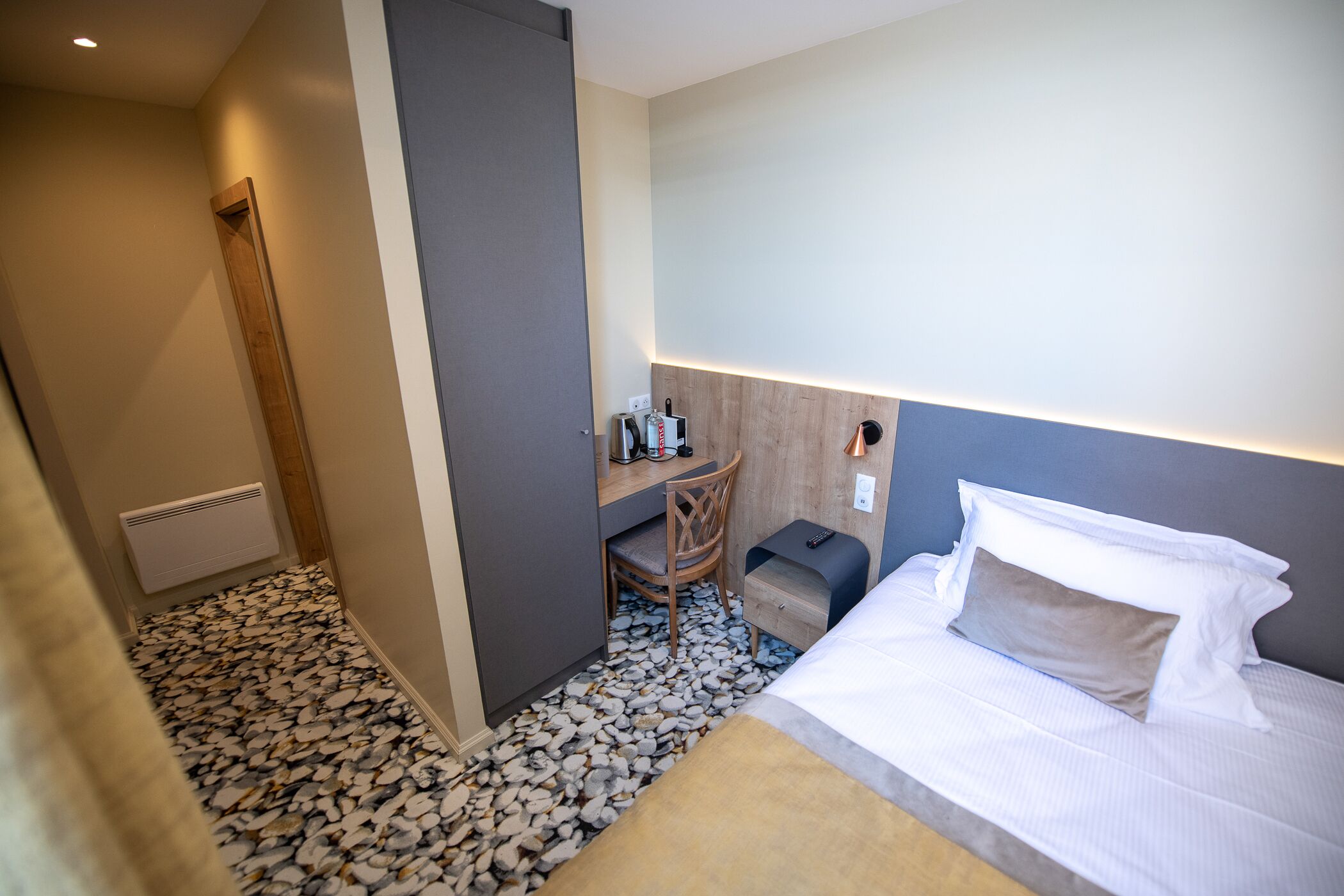 A hotel room with a bed, a desk, a chair, and a small table.