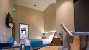 Een hotelkamer met een bed, nachtkastje, spiegel, hanglamp en een kleine potplant.